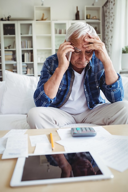 Gespannen senior man praten op mobiele telefoon