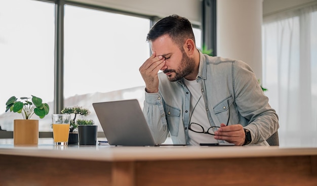 Gespannen zakenman die op laptop werkt terwijl hij aan een bureau zit op kantoor