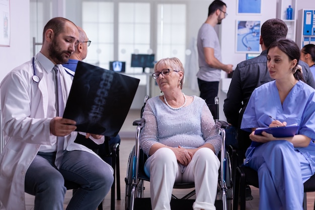 Gespecialiseerde arts die naar de röntgenfoto van de patiënt kijkt en de diagnose uitlegt aan de verpleegster