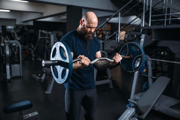 Gespierde atleet in sportkleding doen oefening met barbell, training in de sportschool.