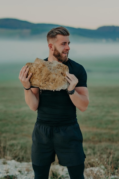 Gespierde atleet man traint en oefent met grote steen