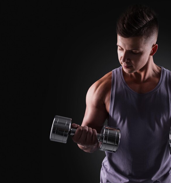 Gespierde atletische knappe man met een metalen halter traint biceps geïsoleerd op zwarte achtergrond Sportieve man Kopieer ruimte voor ontwerp en tekst