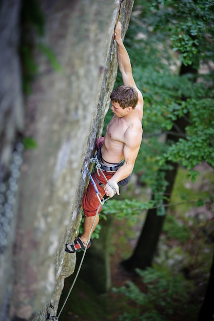 Gespierde bergbeklimmer klimt op overhangende klif