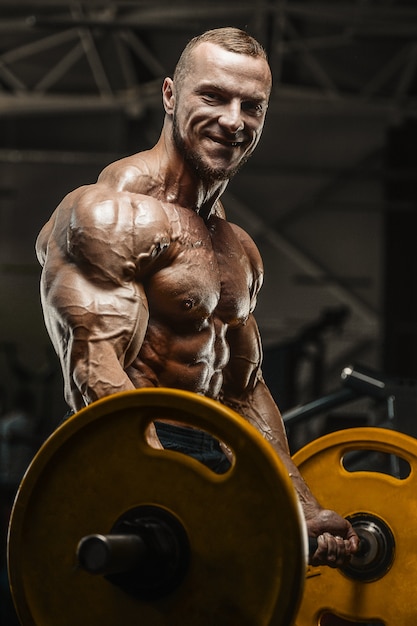 Gespierde bodybuilder fitness man doet armen oefeningen in de sportschool