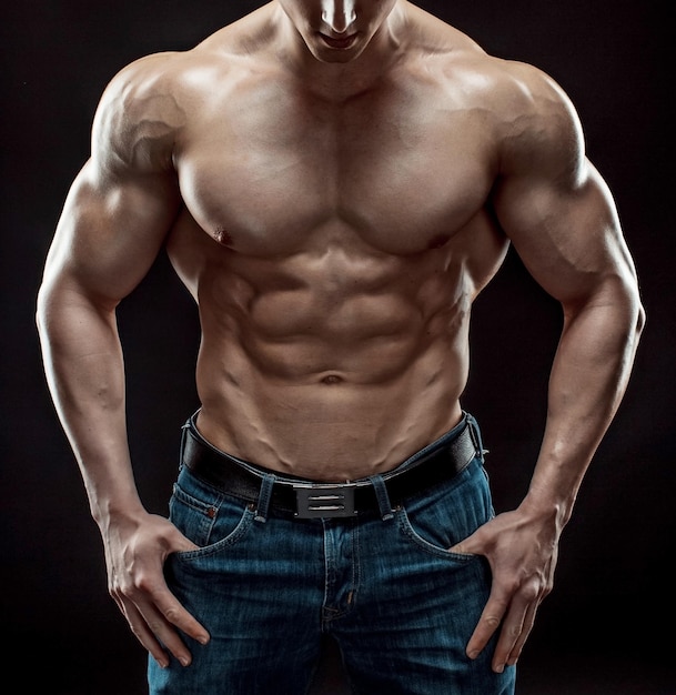 Gespierde bodybuilder man doet poseren op zwarte achtergrond