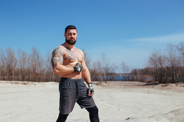 Gespierde bokser traint op het zand met een naakte torso