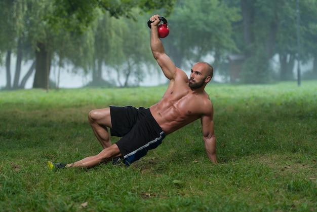 Gespierde Fitness Man Balanceert Kettlebells Met Een Hand Oefening Buitenshuis