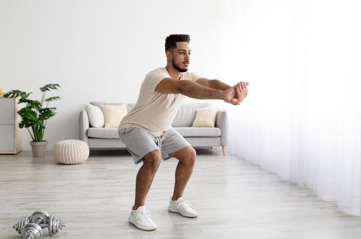 Gespierde jonge Arabische man die squats doet en thuis kopieert