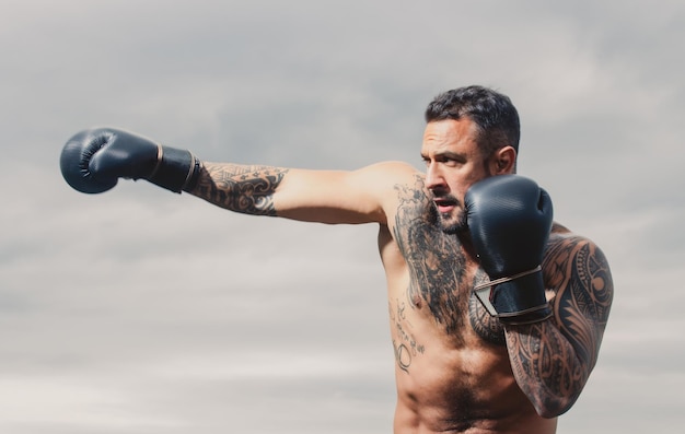 Gespierde kickbokser of muay thai vechter ponsen Kickboksjager in bokshandschoenen die schaduwtraining raken voor competitie Boksstempel