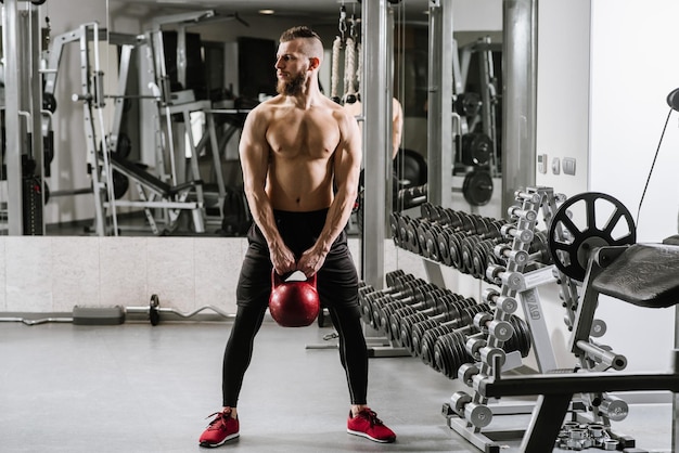 Gespierde man doet oefeningen met een grote halter in de sportschool