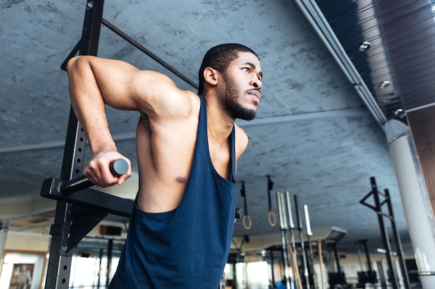 Gespierde man doet pull-ups in de sportschool met sportuitrusting