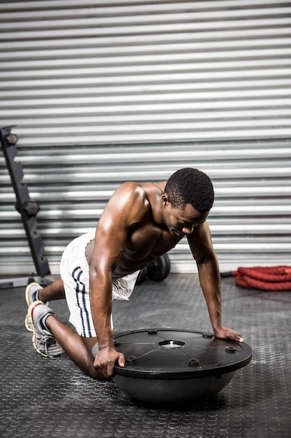 Gespierde man doet push up op bosu bal op de crossfit gym