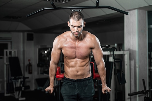 Gespierde man doet push-ups op ongelijke balken in crossfit gym,