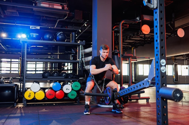 Gespierde man doet zware oefeningen in de moderne sportschool. Sporten in de sportschool