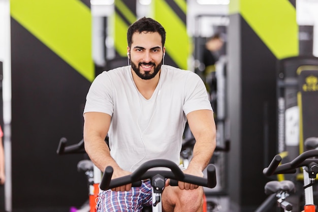 Gespierde man fietsen op hometrainer in de sportschool