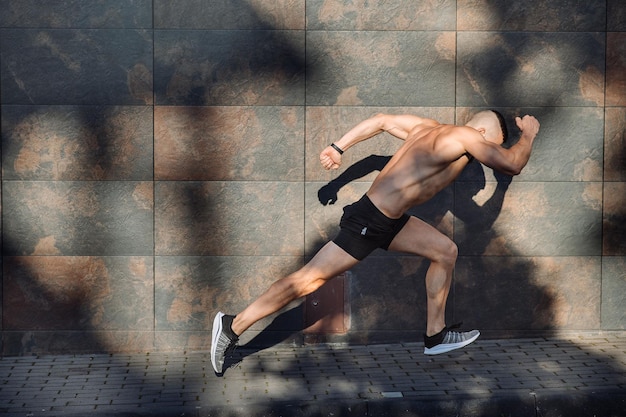 Gespierde man fitnesscoach loopt vanuit een lage start