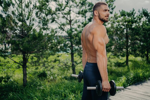 Gespierde man heft gewichten op motiveert buiten Street workout inspiratie