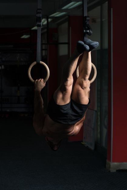 Gespierde man houdt gymnastiekringen vast