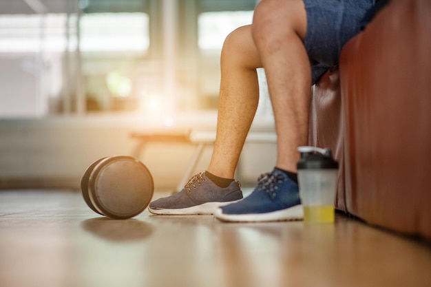 Gespierde man in de sportschool die een pauze neemt van de training naast de fles mineraalzout en halters