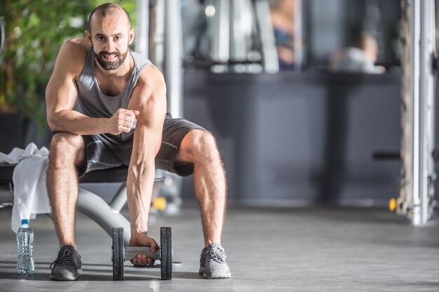 Gespierde man oefenen met halters in de fitnessruimte.