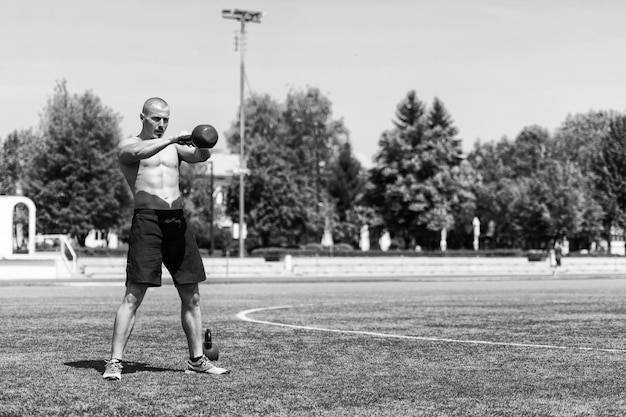 Gespierde man oefenen met Kettlebell buiten