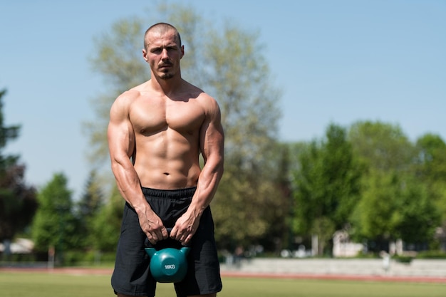 Gespierde man oefenen met Kettlebell buiten