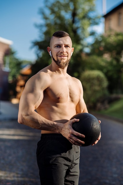 Gespierde man of fitnesscoach met fitnessgewichtbal buitenshuis