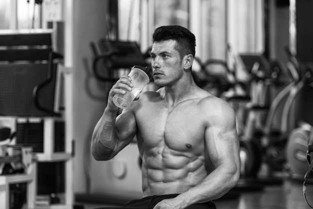 Gespierde man rust na het sporten en drinken uit shaker