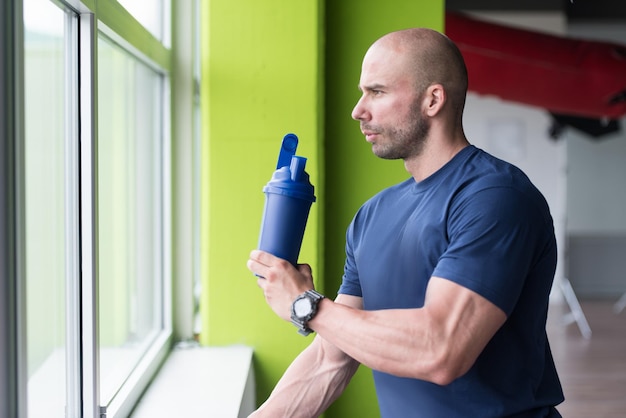 Gespierde man rust na het sporten en drinken uit shaker