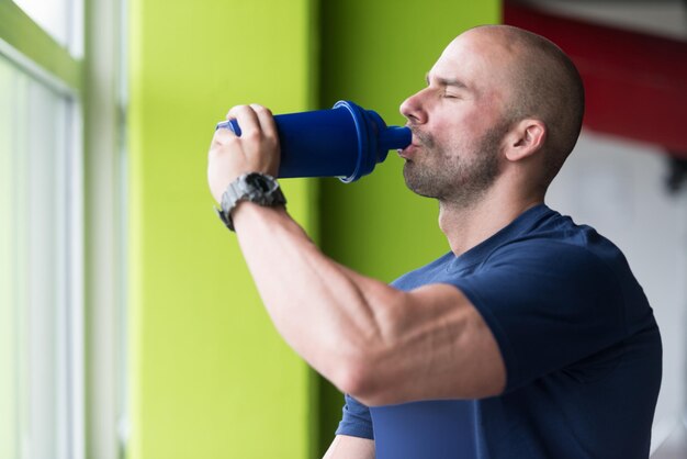 Gespierde man rust na het sporten en drinken uit shaker