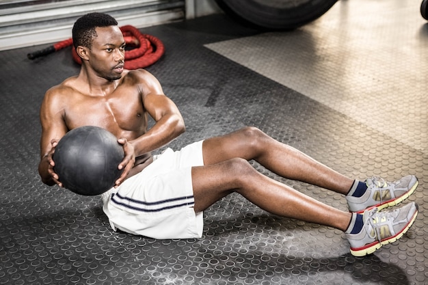 Gespierde man training met medicijnbal op de crossfit gym