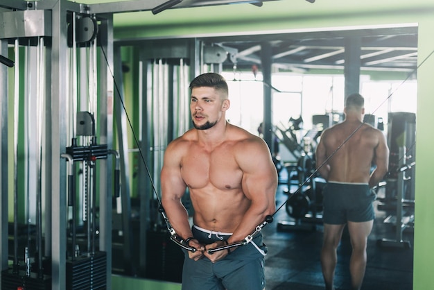 Gespierde man traint in de sportschool en doet oefeningen op triceps sterke mannelijke naakte torso