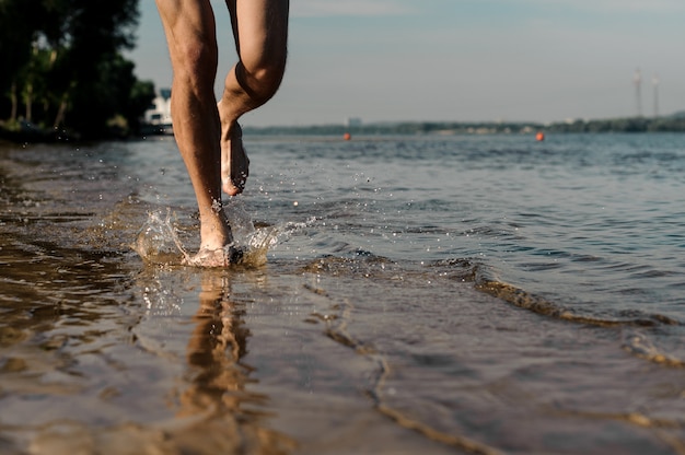 Gespierde mannelijke voeten lopen langs de prachtige rivieroever