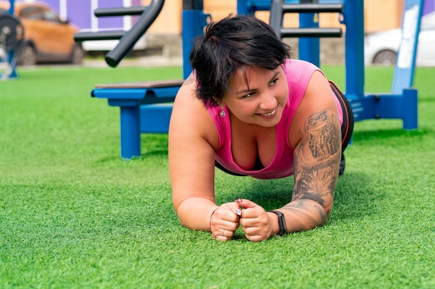 Gespierde mollige vrouw die oefeningen op het sportveld uitvoert