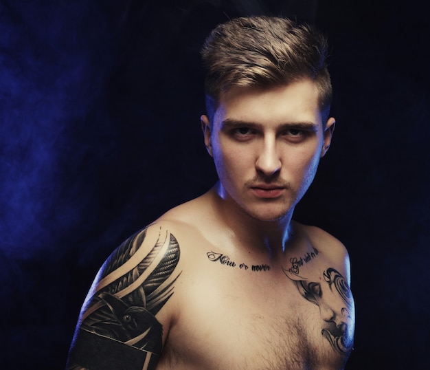 Gespierde sexy man met tatoeage over donkere achtergrond