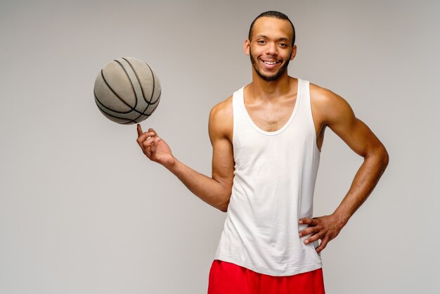 Gespierde sportman basketbal spelen over lichtgrijze muur