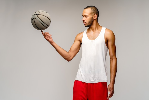 Gespierde sportman basketbal spelen over lichtgrijze muur