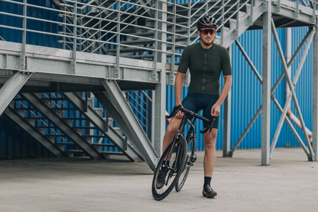 Gespierde wielrenner zittend op de fiets over blauwe muur met trappen