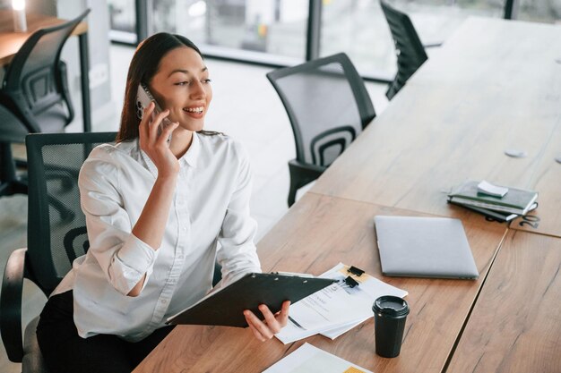 Gesprek via de telefoon zakenvrouw is binnen in het kantoor