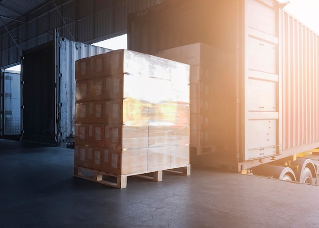 Gestapelde pakketdozen die worden geladen met vrachtcontainervrachtwagens die worden geladen in het dokmagazijn