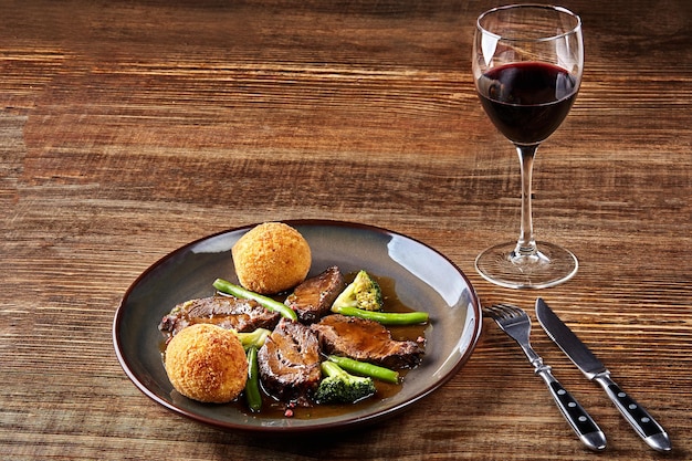 Gestoofd rundvlees met groenten en een glas rode droge wijn op houten tafel close-up Hot Meat Dishes