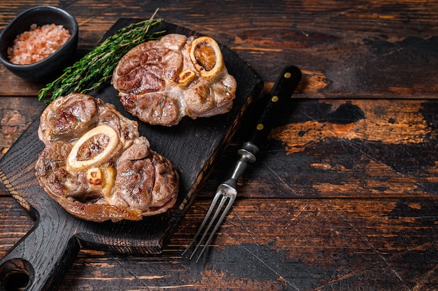 Gestoofd vlees op het bot osso buco beef schacht, italiaanse ossobuco steak. donkere houten achtergrond. bovenaanzicht. ruimte kopiëren.