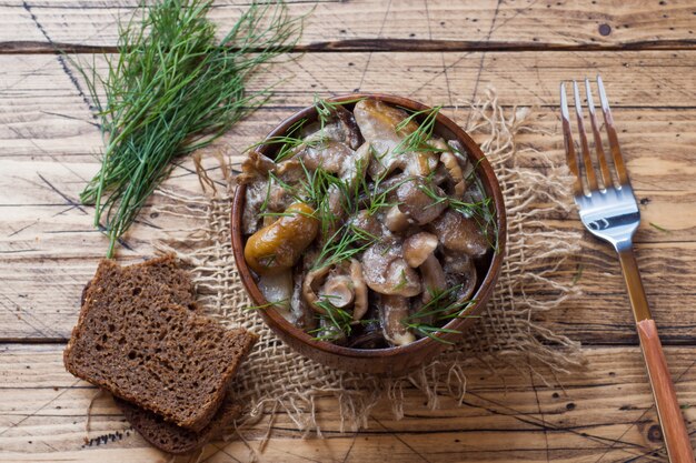 Gestoofde champignons in een saus met zure room en kaas in een houten kom.