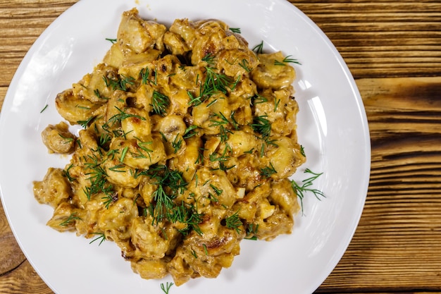 Gestoofde champignons met zure room op houten tafel Top view