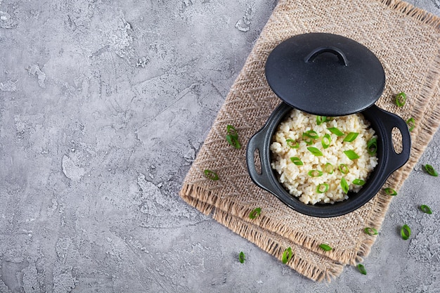 Gestoofde rijst met kip in een pot op grijze achtergrond bovenaanzicht