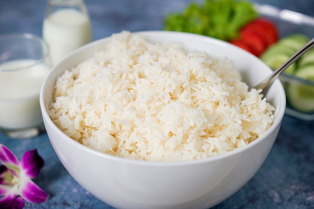 Gestoomde rijst in een witte kom op blauwe achtergrond