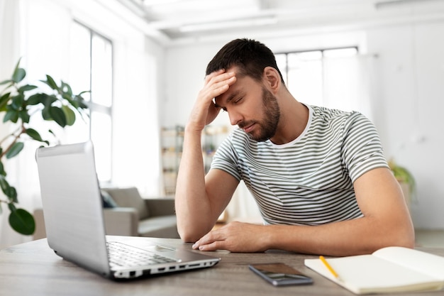 gestresseerde man met laptop die thuis op kantoor werkt