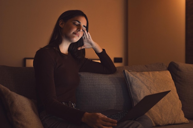 Gestresseerde vrouw laat in de nacht met een sterke vreselijke hoofdpijn aanval na computer laptop studie slaperig uitgeput meisje dat lijdt aan chronische migraine masseren tempels om hoofdpijn spanning te verlichtenxA