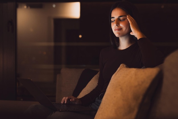 Gestresseerde vrouw laat in de nacht met een sterke vreselijke hoofdpijn aanval na computer laptop studie slaperig uitgeput meisje dat lijdt aan chronische migraine masseren tempels om hoofdpijn spanning te verlichtenxA