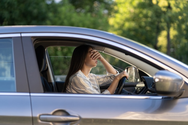 Gestresst meisje met hoofdpijn rijdt auto gefrustreerd ontevreden jonge vrouwelijke bestuurder lijdt aan ziekte